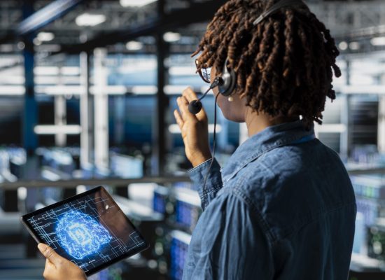 Server hub IT specialist monitoring systems and doing tech support, guiding users through troubleshooting steps. African american expert providing remote diagnostics using headset mic.